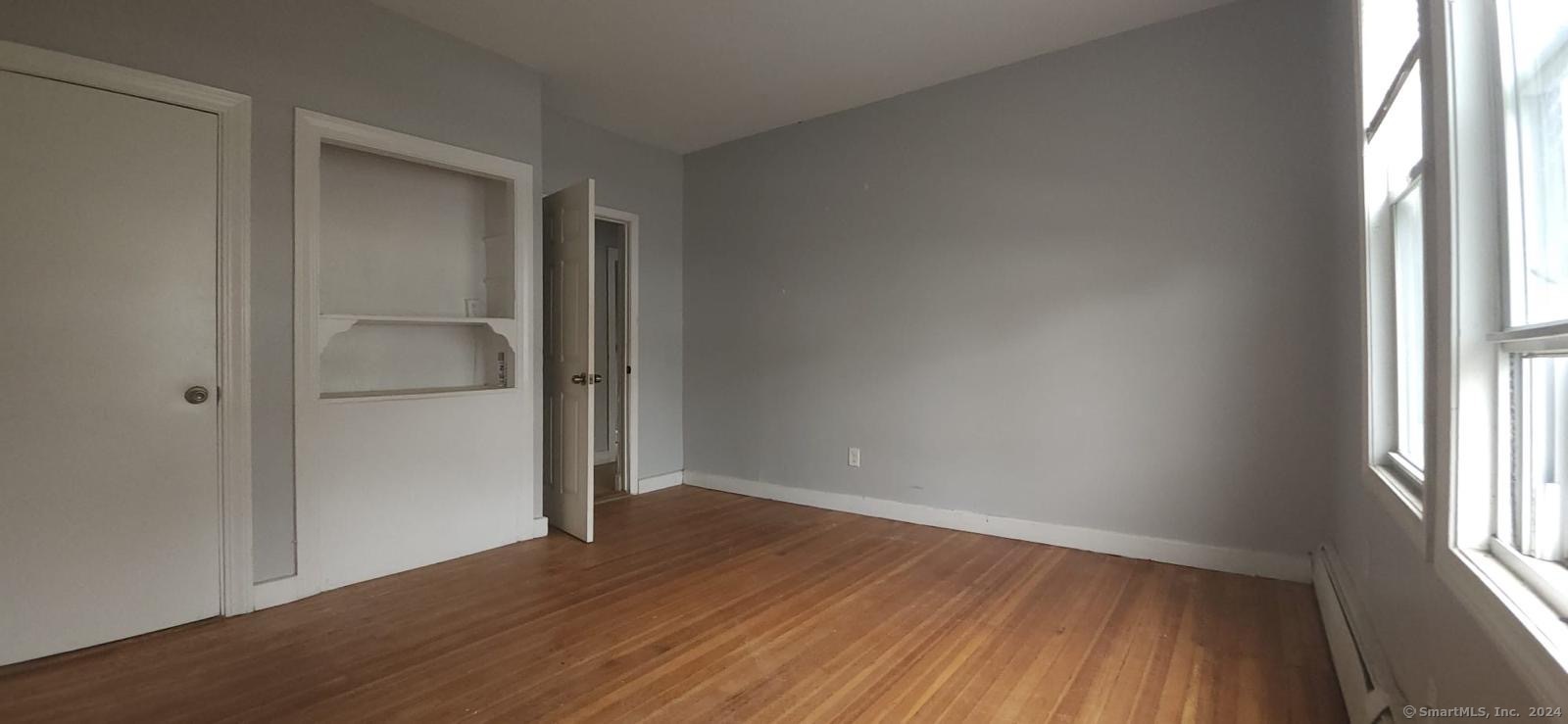 an empty room with wooden floor cabinet and windows