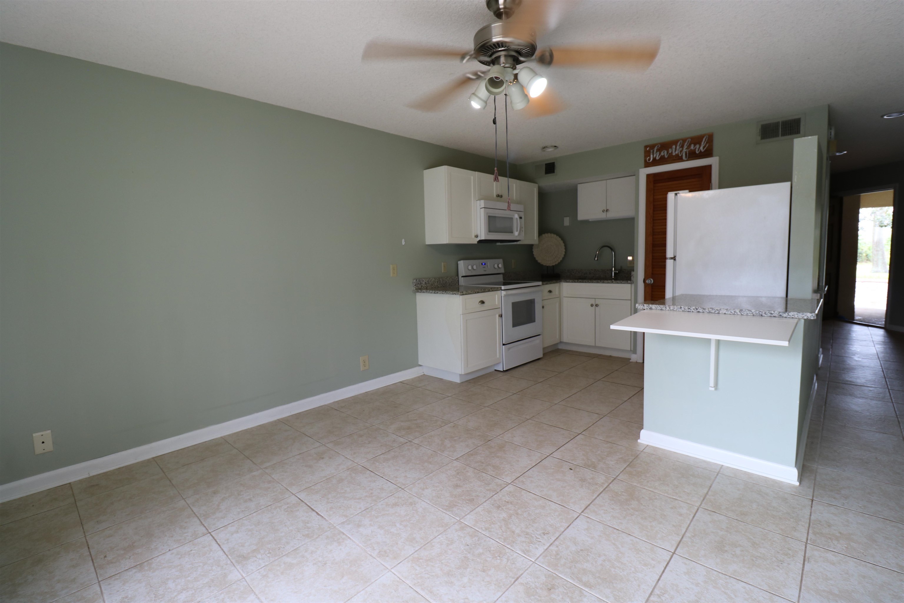 a view of a kitchen with a sink and dishwasher a stove top oven with wooden floor