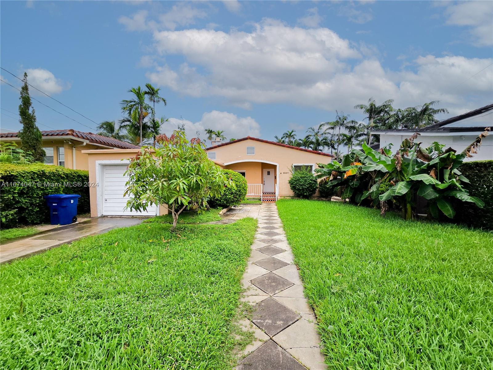 a front view of a house with a yard and potted plants