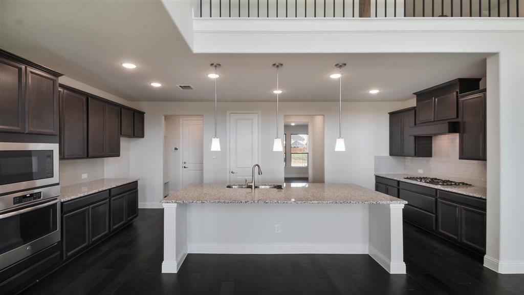 a kitchen with stainless steel appliances kitchen island granite countertop a stove a sink and a refrigerator