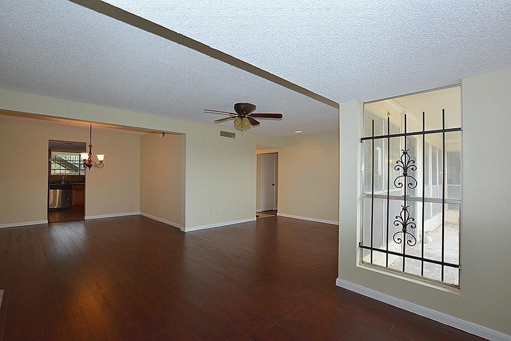 an empty room with wooden floor cabinet and windows