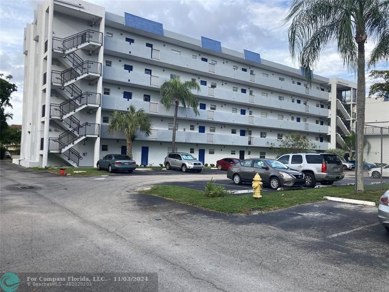 a view of a building with a yard and parking space