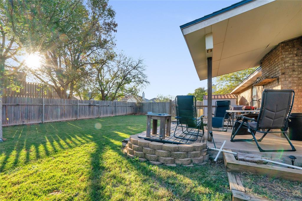 a view of a backyard with table and chairs potted plants and wooden fence