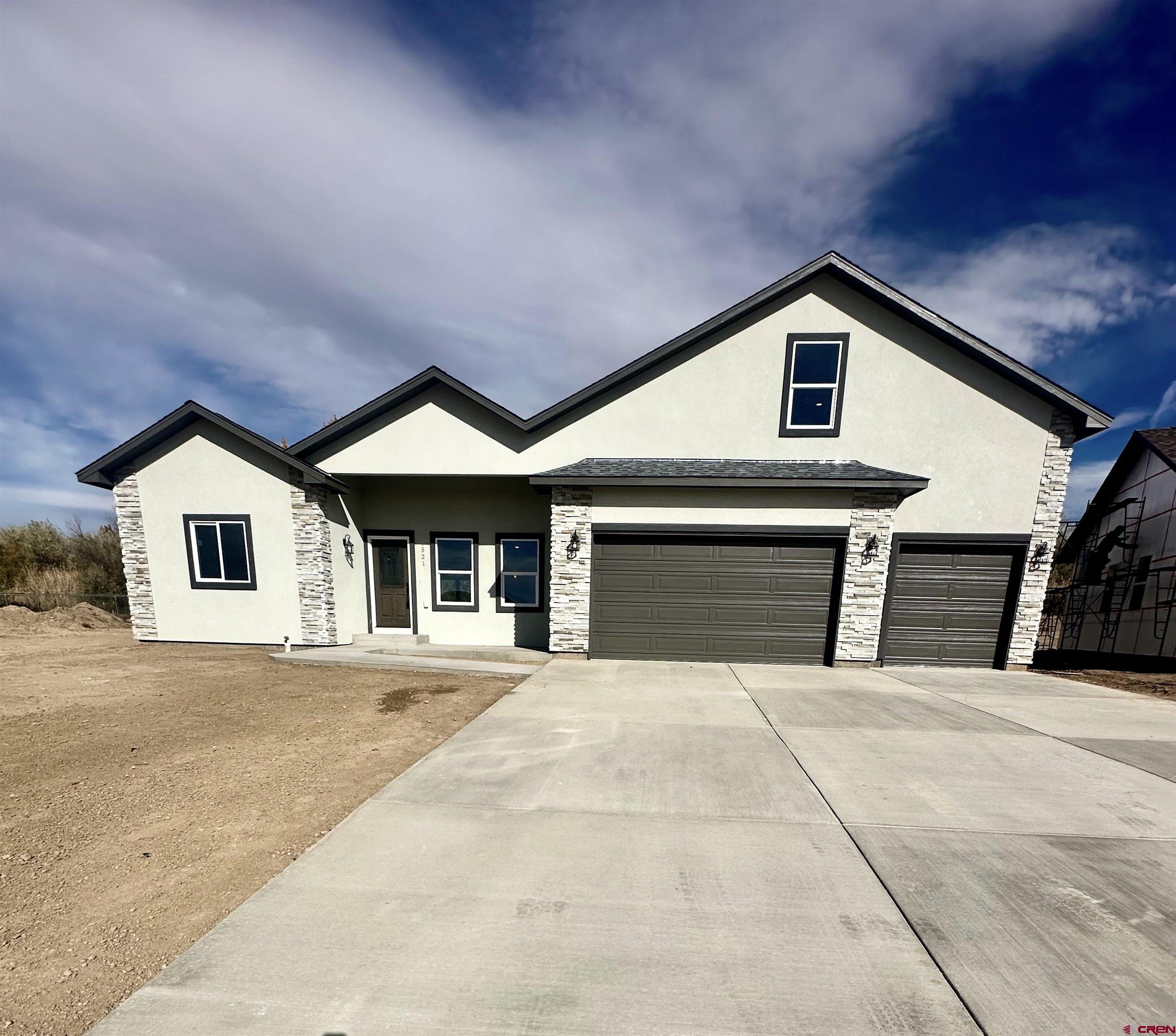 a front view of a house with yard and parking area