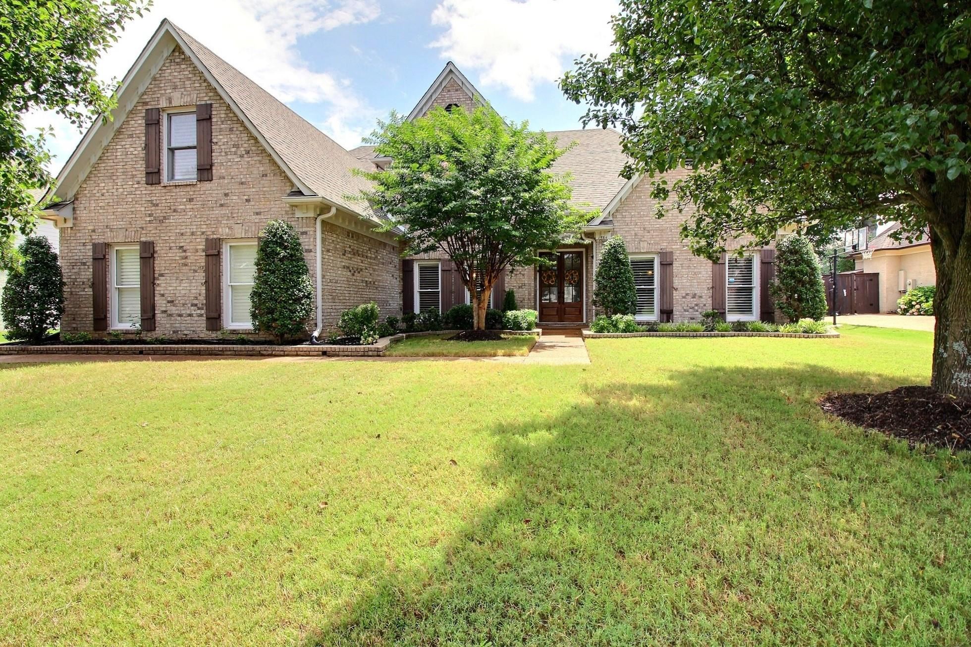 a front view of a house with a yard and trees