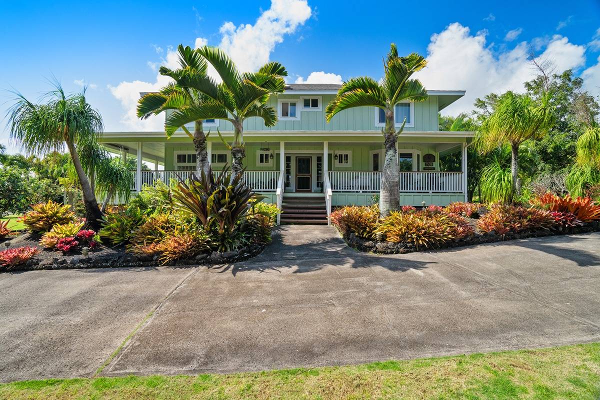 a front view of a house with a yard and potted plants