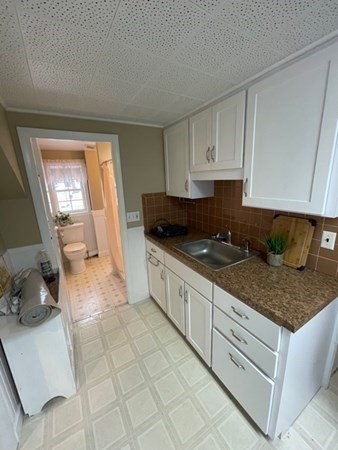 a kitchen with granite countertop a sink a stove and cabinets