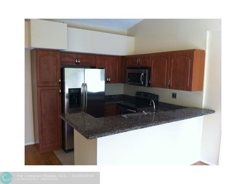 a kitchen with stainless steel appliances granite countertop a sink and a refrigerator