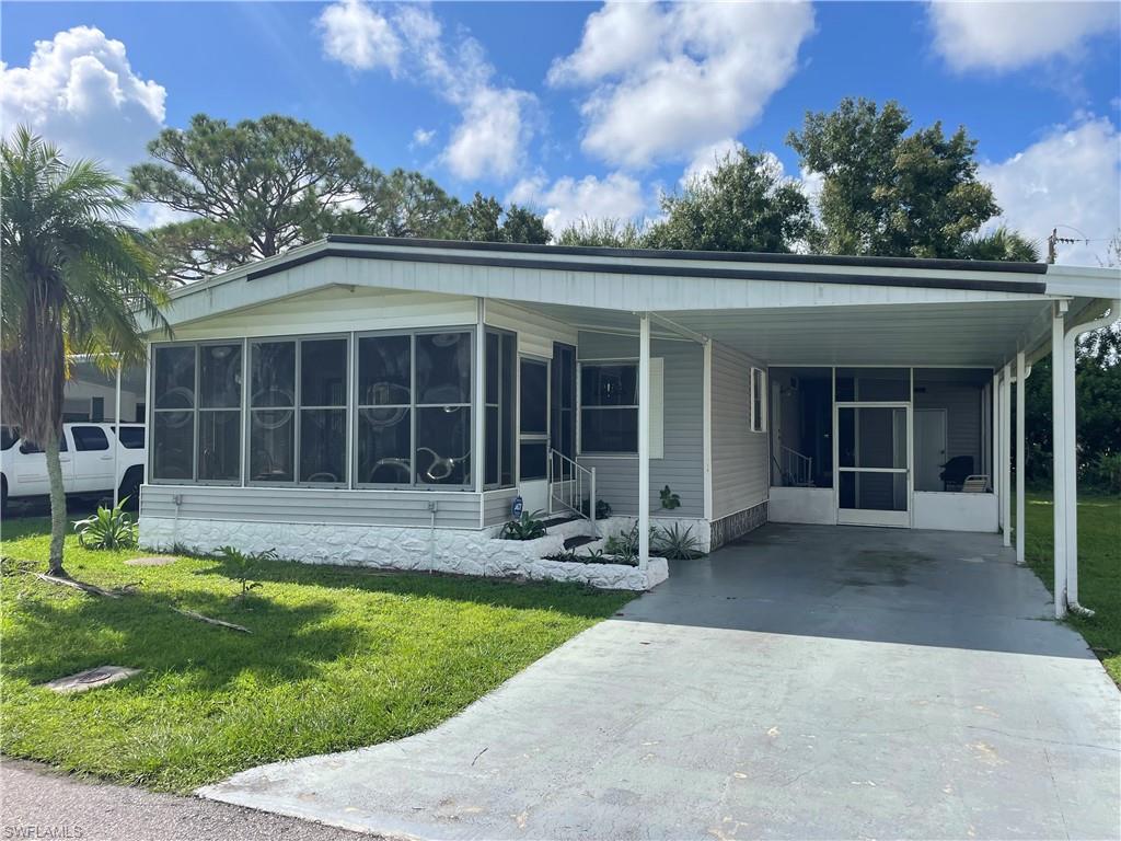 Manufactured / mobile home with a front yard, a sunroom, and a carport