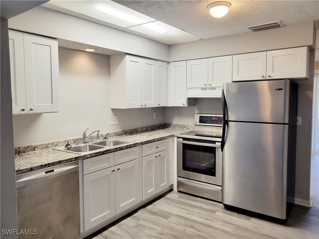 a kitchen with a refrigerator sink and cabinets