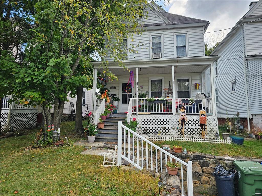 View of front of property featuring a front yard, cooling unit, and covered porch