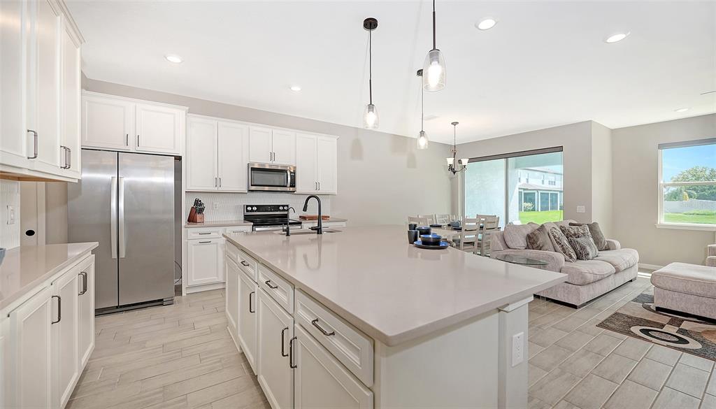 a large kitchen with kitchen island a white counter space a sink appliances and cabinets