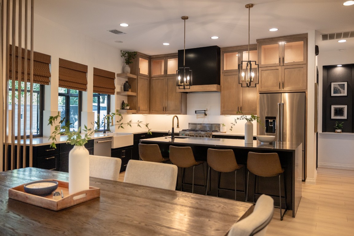 A modernized masterpiece in the kitchen with ample countertop space, a prep sink, pot filler, Verona stove/oven, an under counter microwave are just some of the high-end finishes in this kitchen. Wooden slat divider helps separate the space from the dining area and the wall of curved windows extending into the kitchen provides natural light into the space.