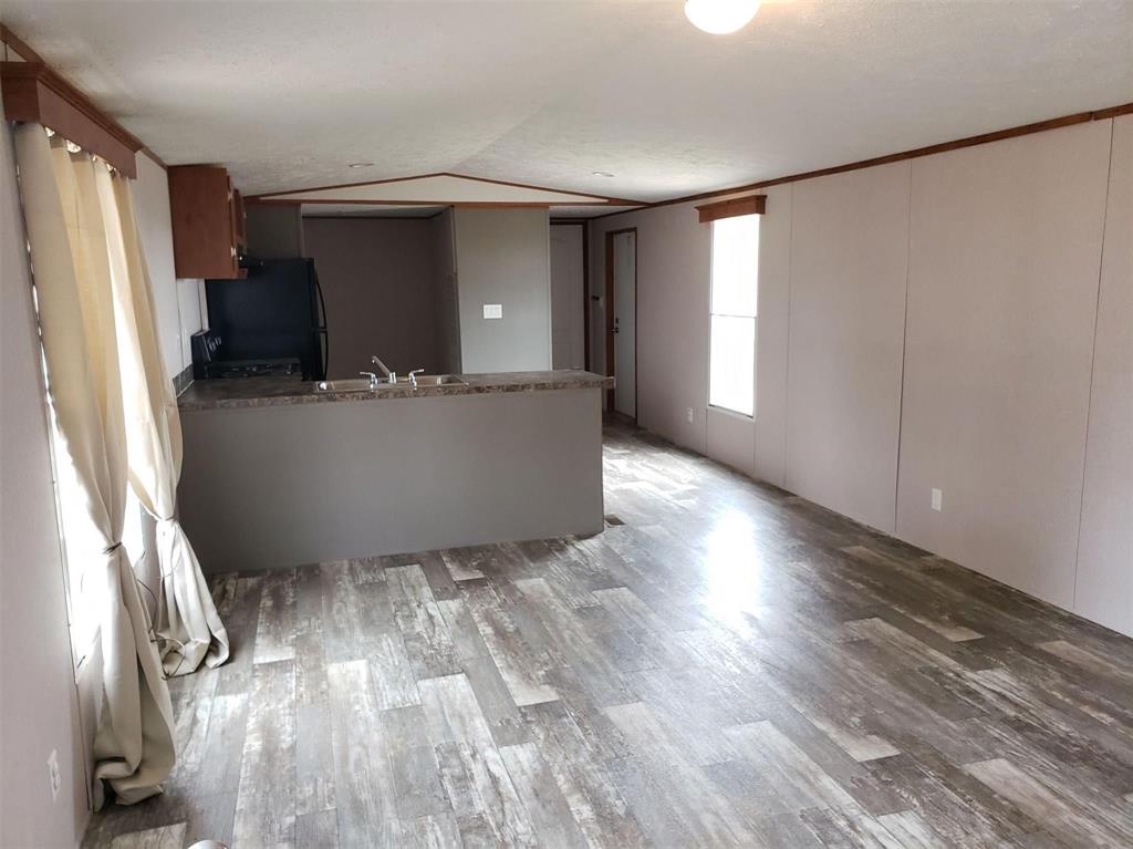 a living room with wooden floor and a refrigerator