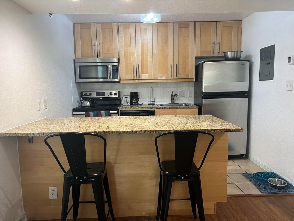 a kitchen with stainless steel appliances granite countertop a table chairs in it and wooden floors