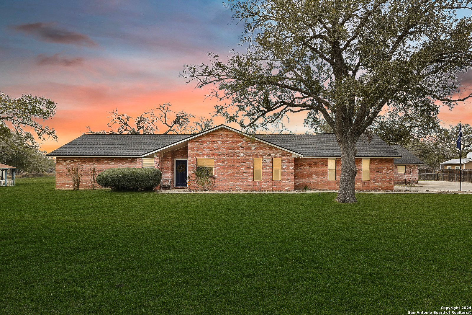 a house that is sitting in the grass with large trees