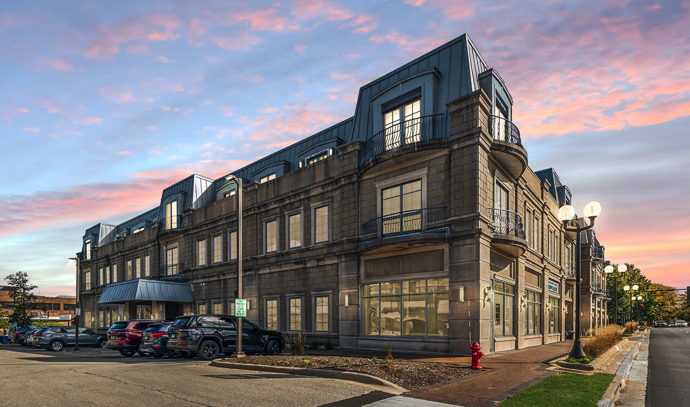 a front view of a building with lot of cars and trees