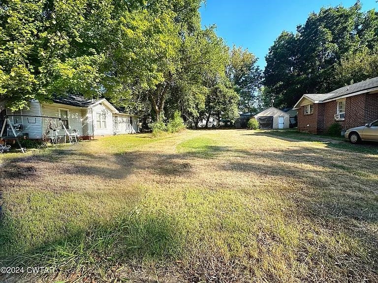 a view of a house with a yard and large trees