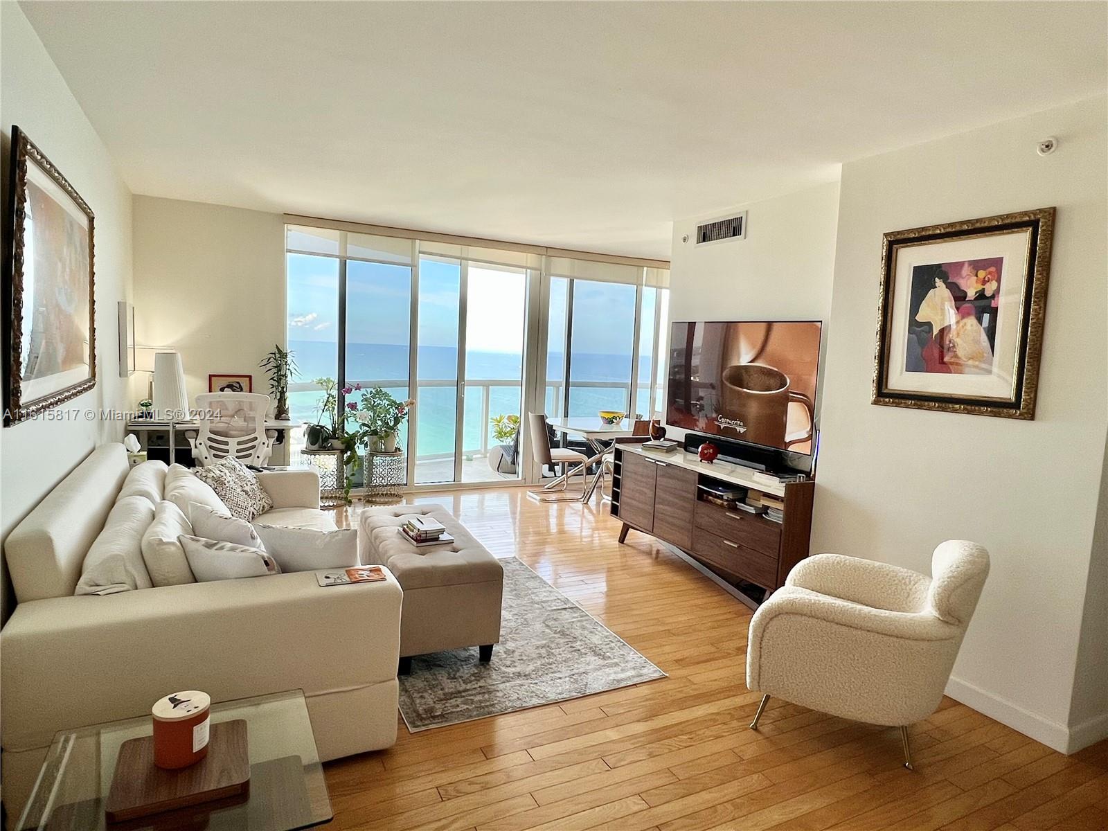 a living room with furniture floor to ceiling window and a flat screen tv