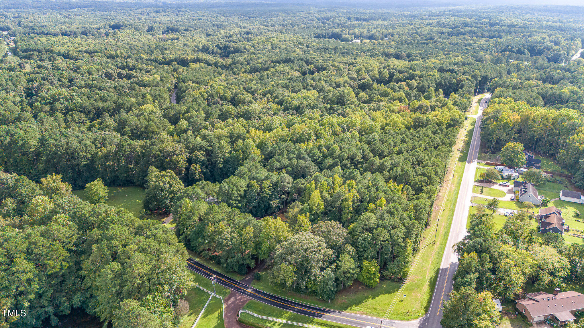 an aerial view of residential house with outdoor space and trees all around