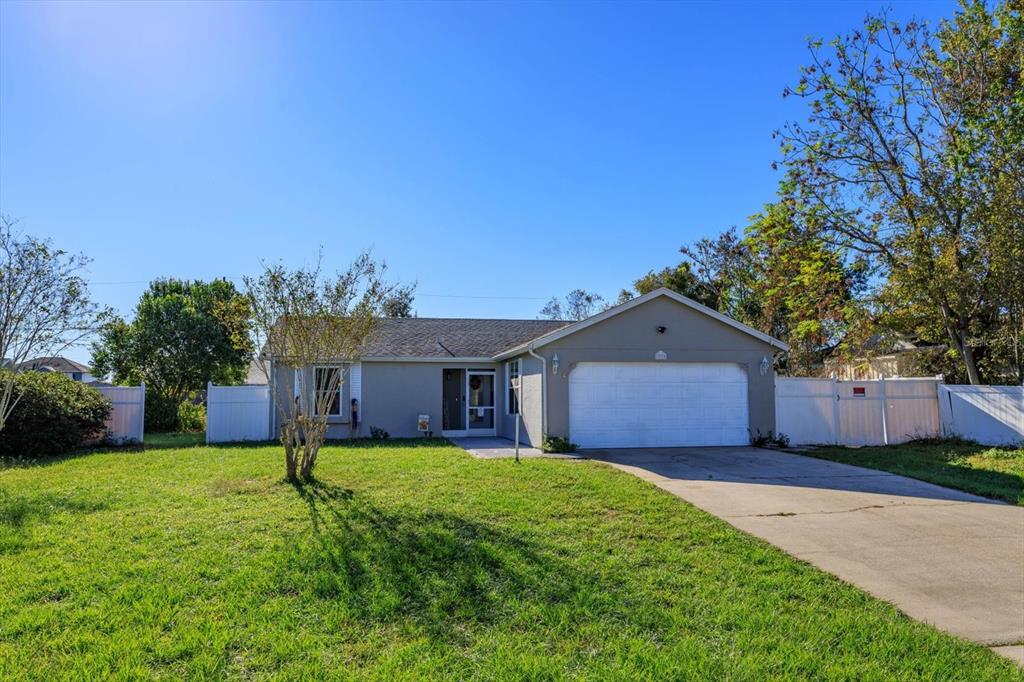 a front view of a house with a yard and large tree