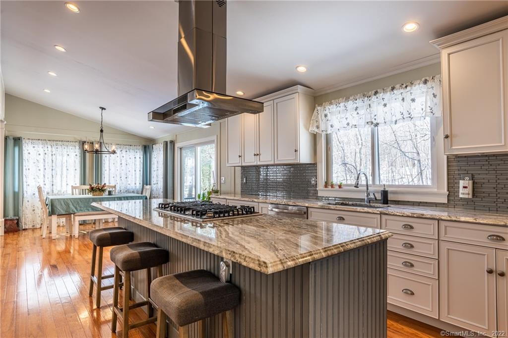 a kitchen with a stove a sink a kitchen island with chairs and wooden cabinets