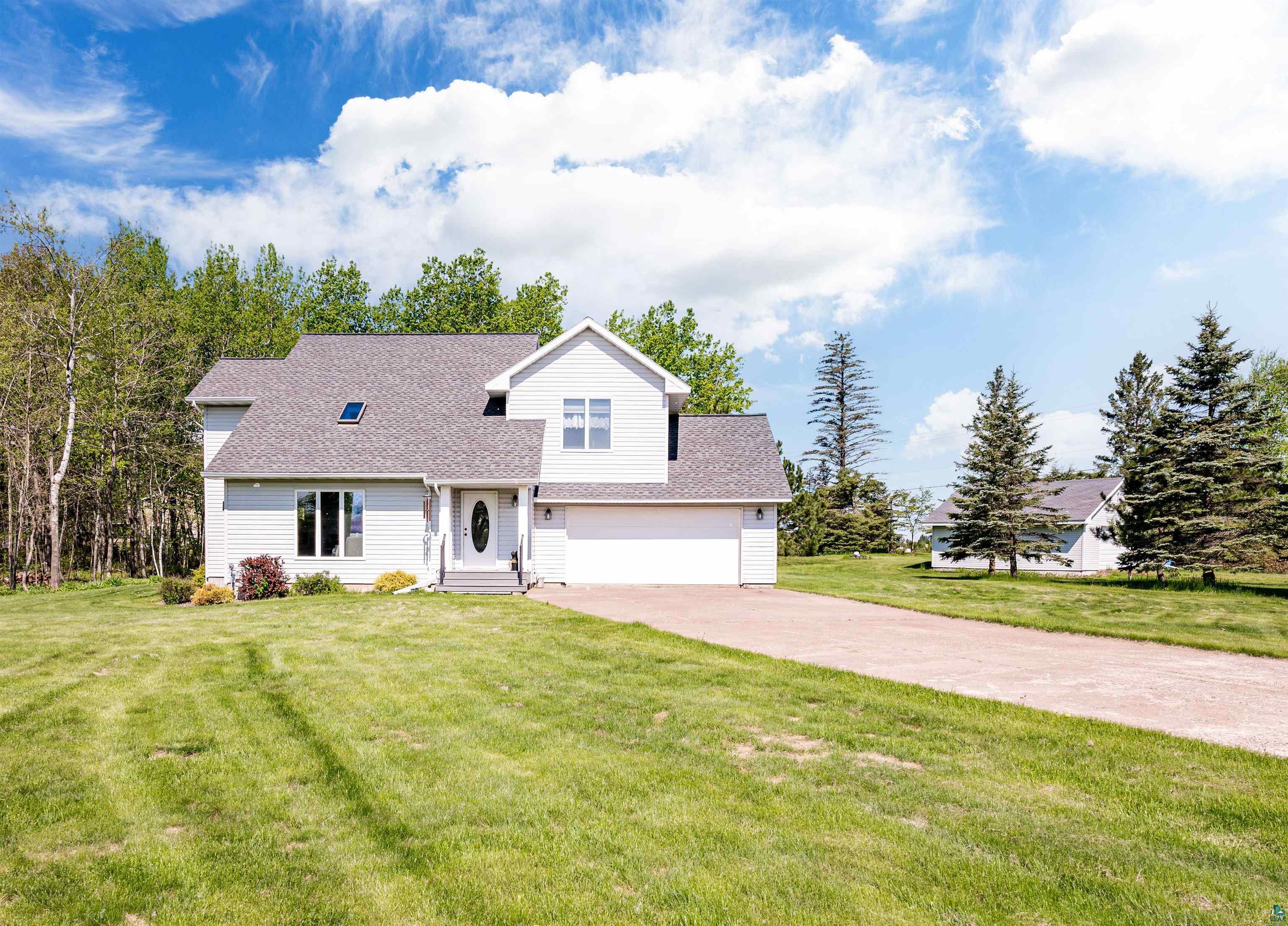 Cape cod home featuring a garage and a front yard