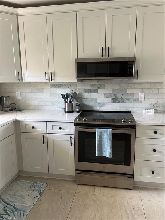 a kitchen with granite countertop white cabinets and stainless steel appliances