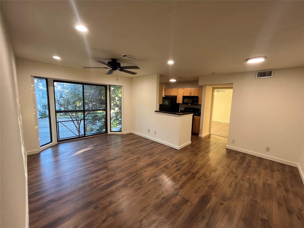 a view of empty room with wooden floor and a window