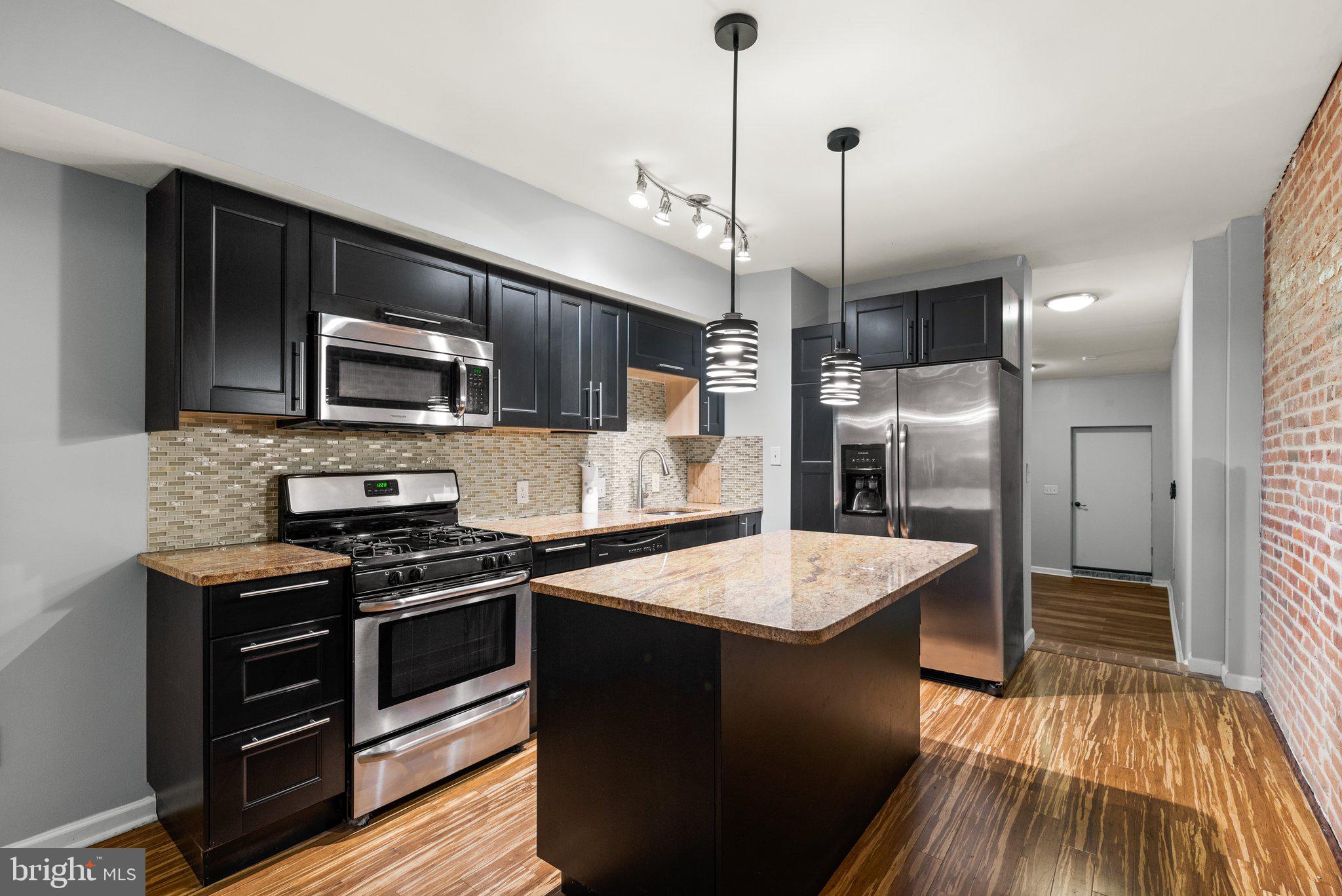 a kitchen with a refrigerator a sink and wooden floor