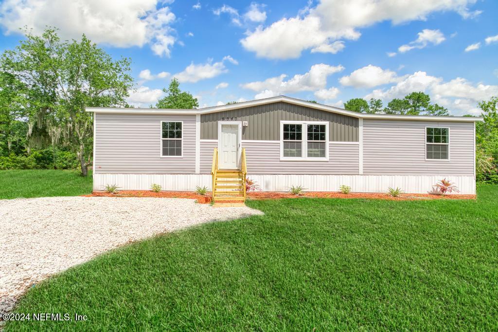 a front view of house with yard and trees in the background