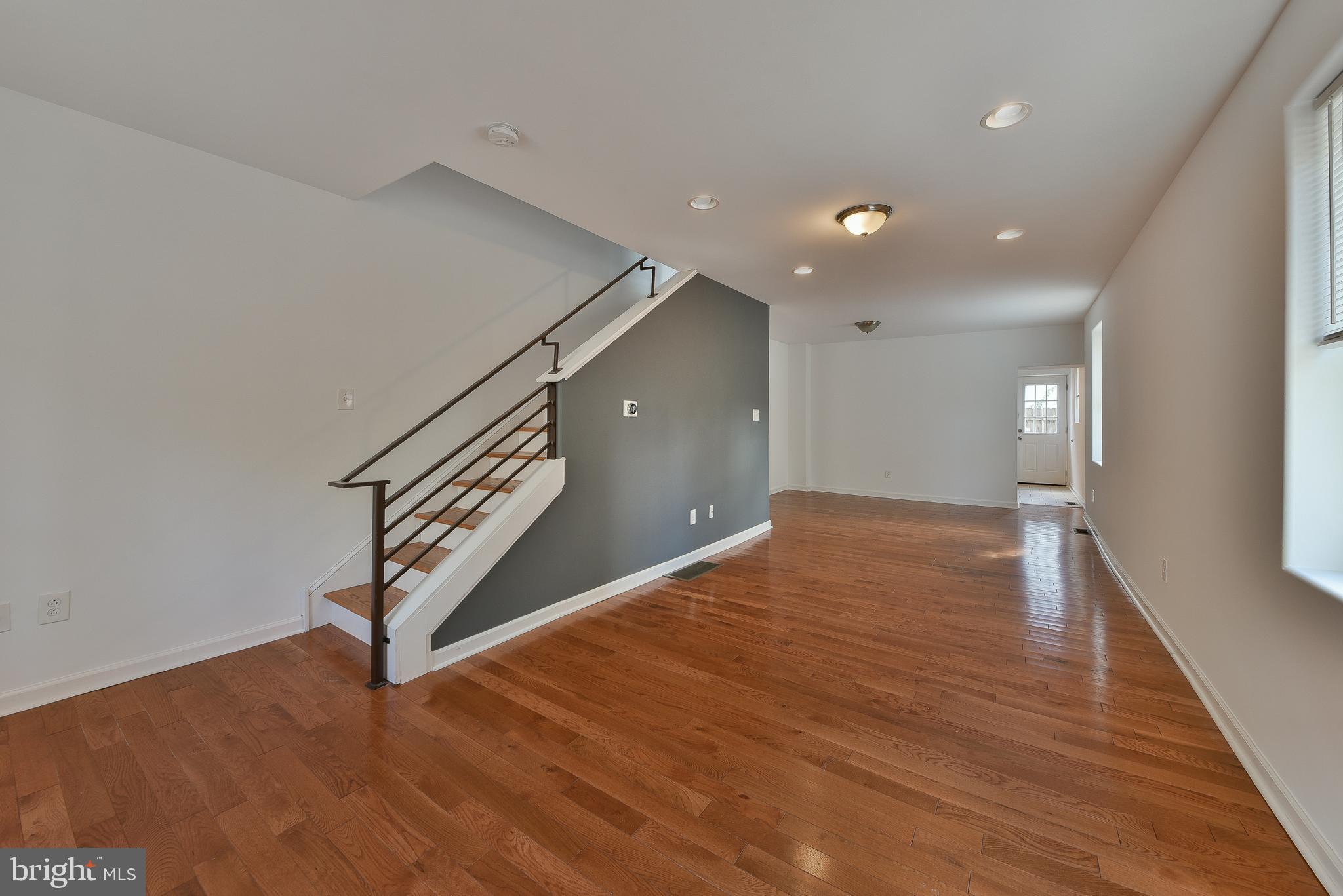 a view of an empty room with wooden floor and stairs