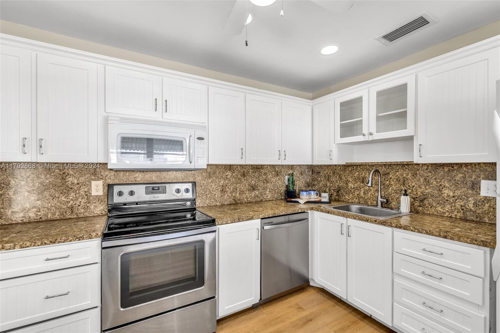 a kitchen with white cabinets stainless steel appliances and sink