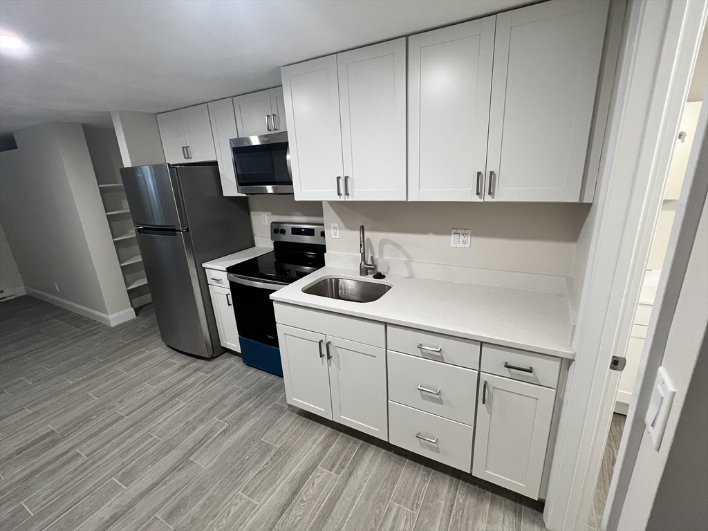 a kitchen with stainless steel appliances white cabinets and wooden floors