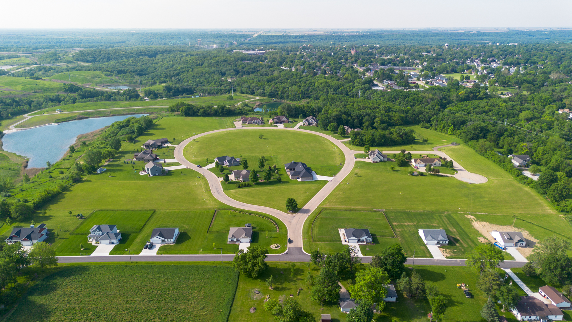 an aerial view of a residential houses with outdoor space and lake view