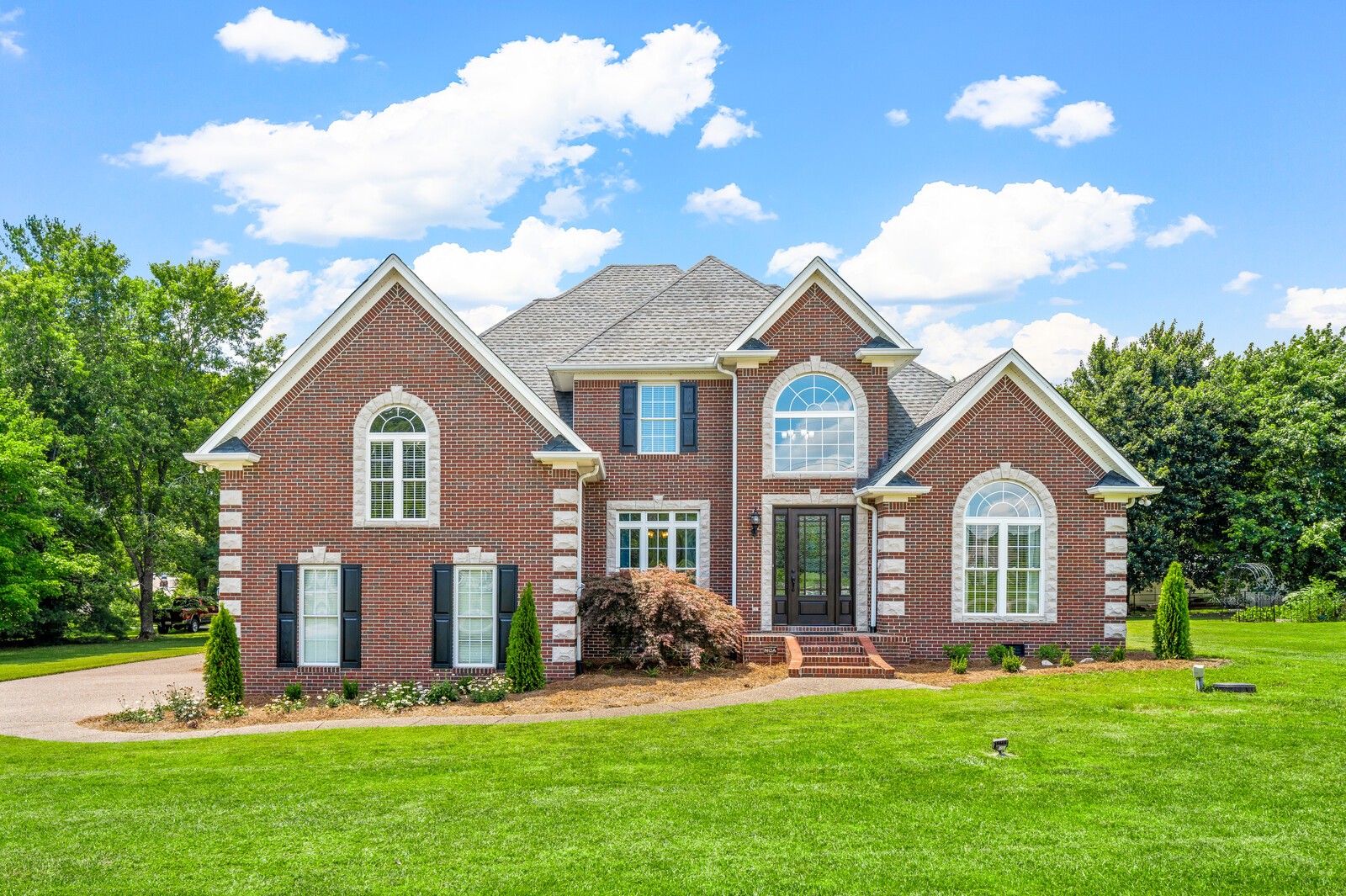 a front view of a house with a garden and trees