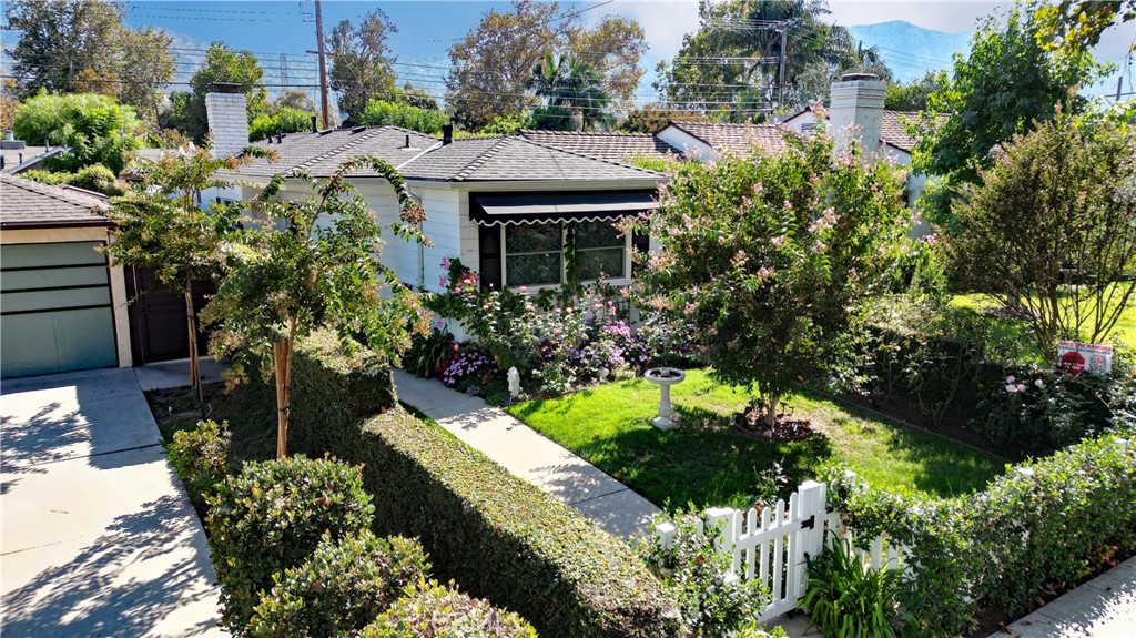 a front view of a house with a yard and covered with flower plants