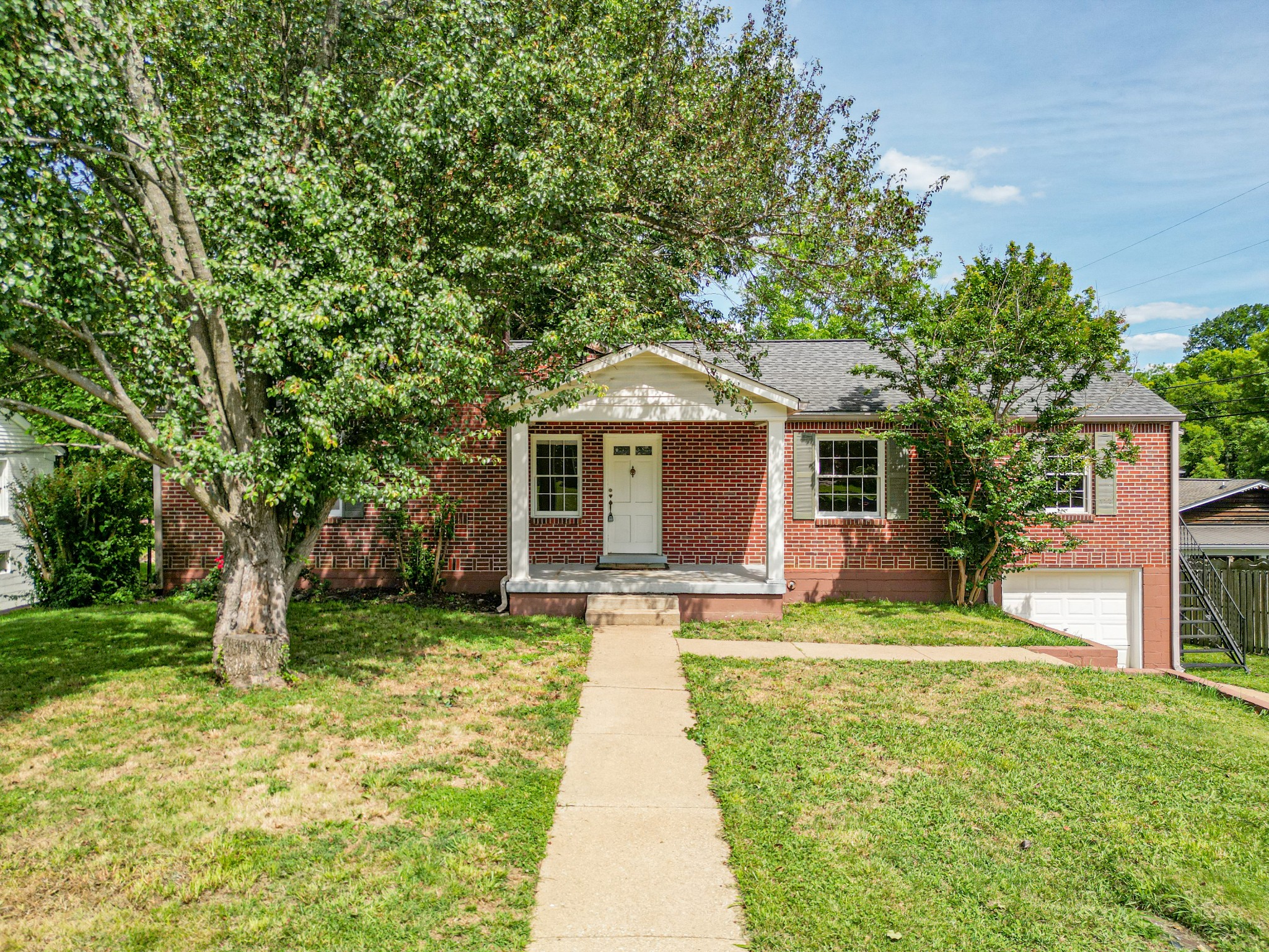 a front view of a house with a yard and trees