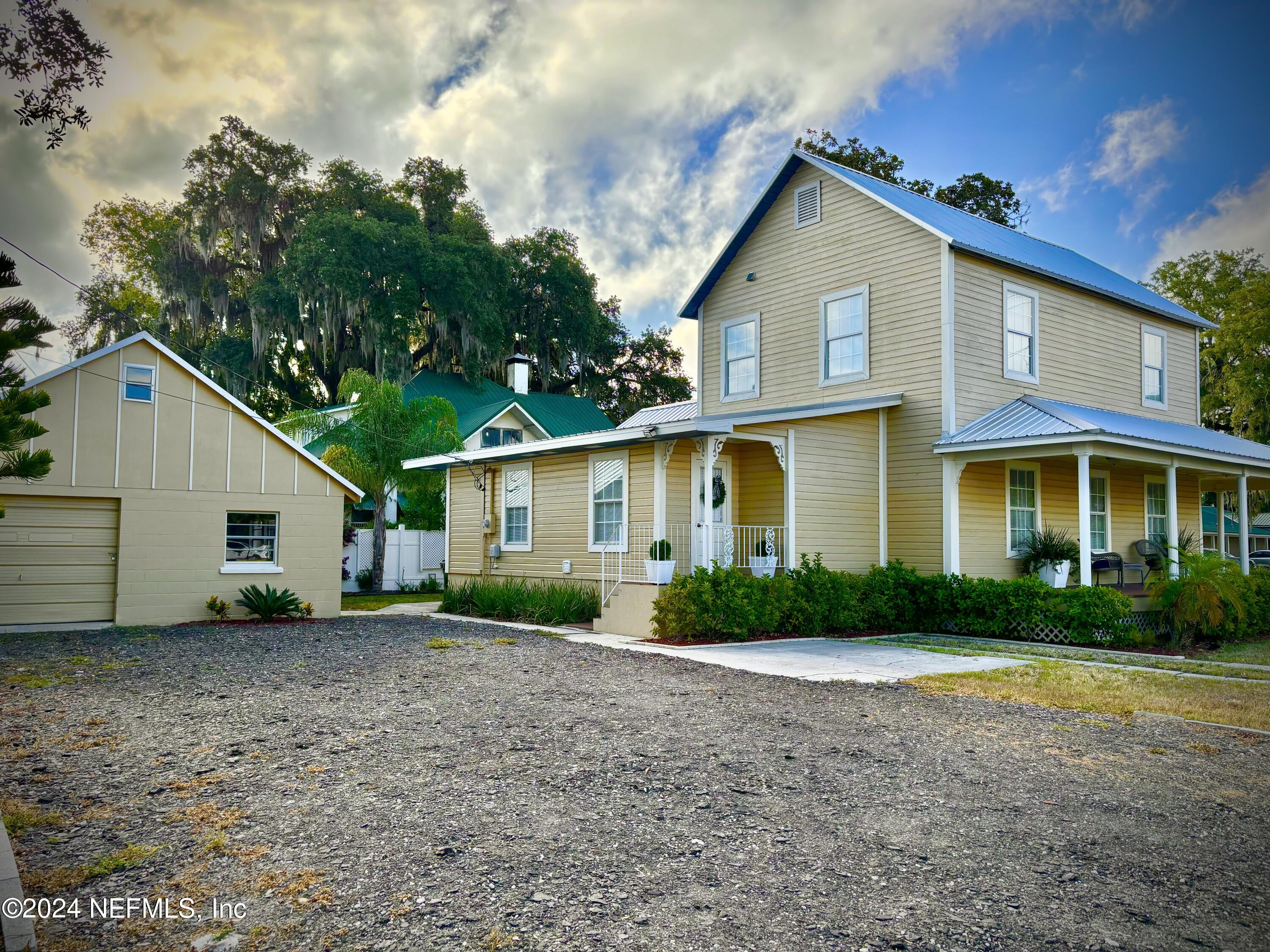 a view of a yard in front of a house with large trees