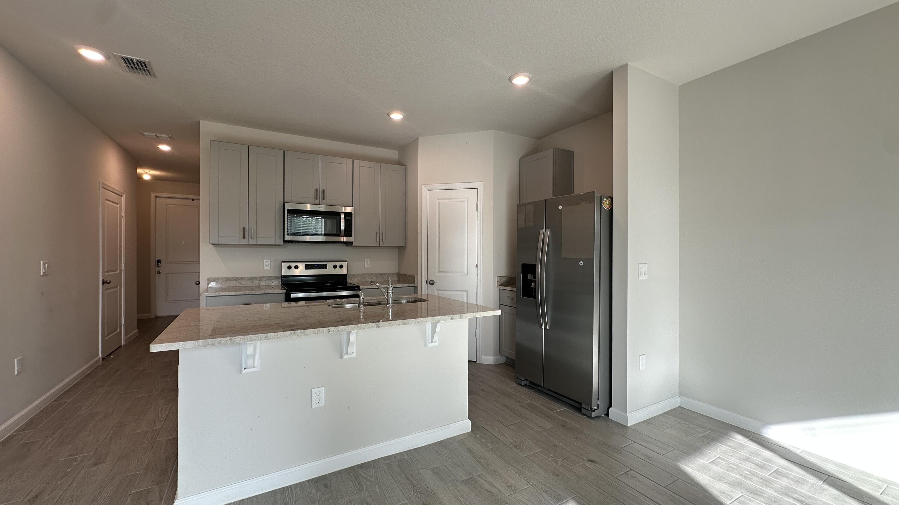 a kitchen with stainless steel appliances granite countertop a refrigerator and a stove top oven