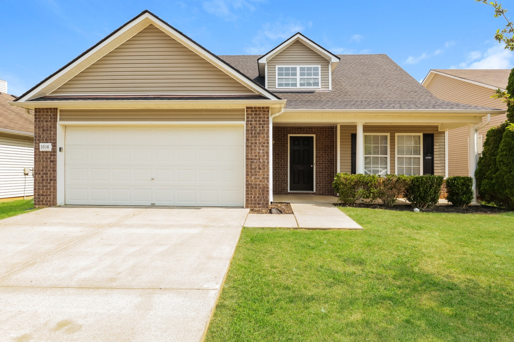 a front view of a house with yard and parking