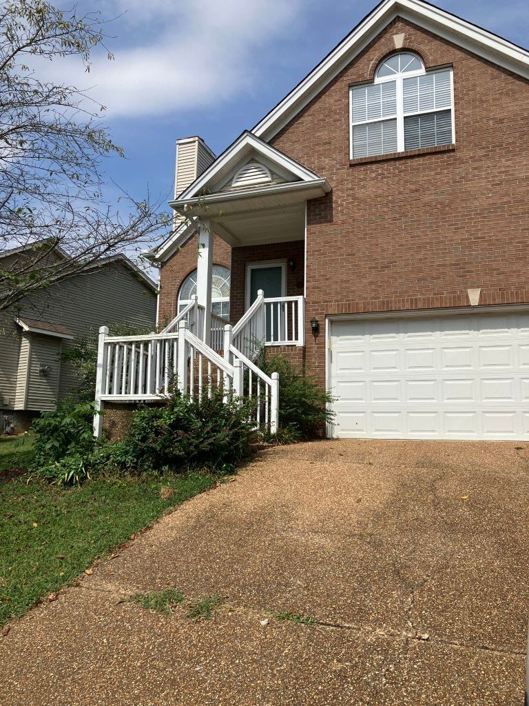 a front view of a house with yard and parking