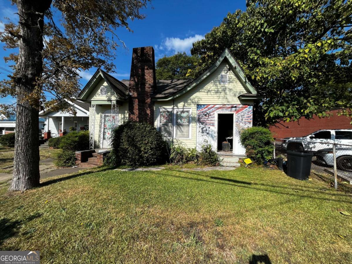 a front view of a house with a garden and trees