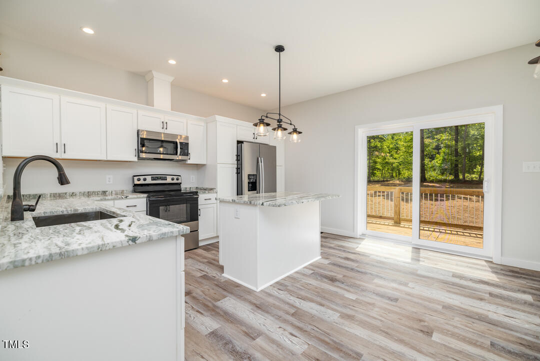 a kitchen with kitchen island granite countertop a stove top oven a sink a counter space and cabinets