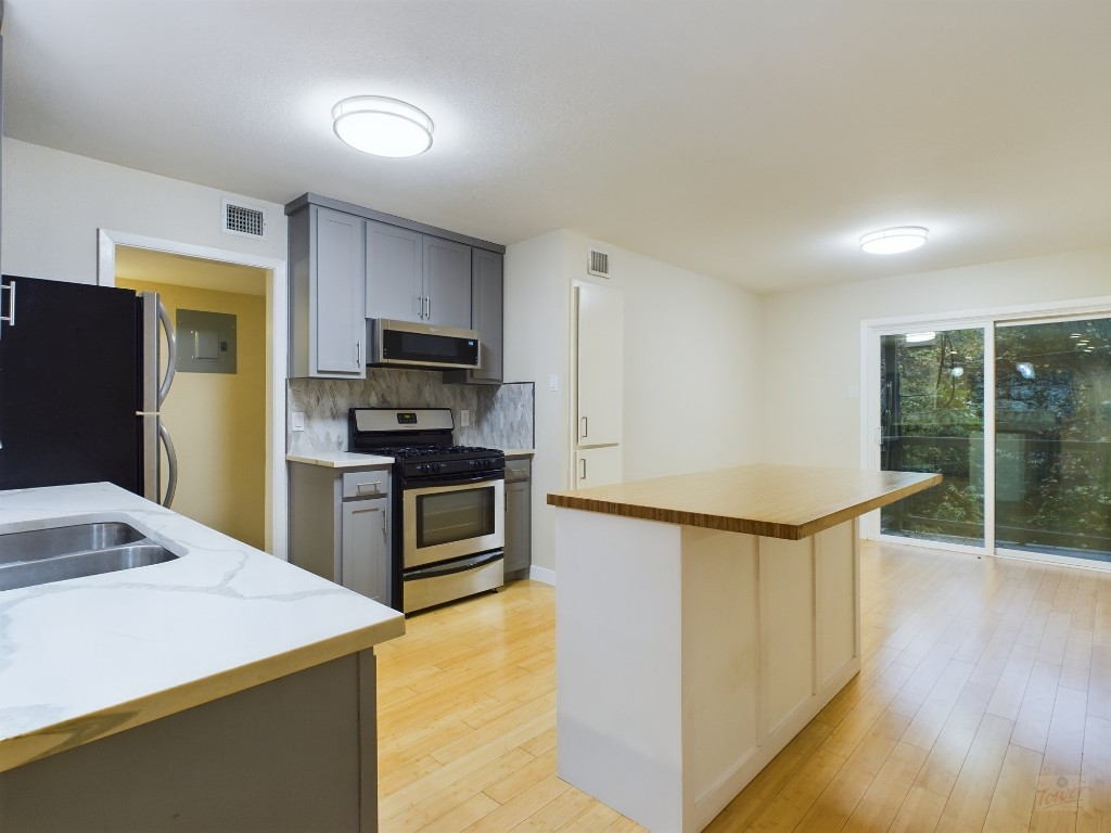 a kitchen with kitchen island a counter top space cabinets stainless steel appliances and wooden floor