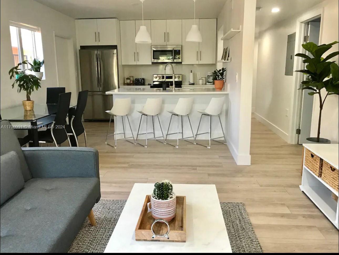 a living room with stainless steel appliances furniture and a wooden floor