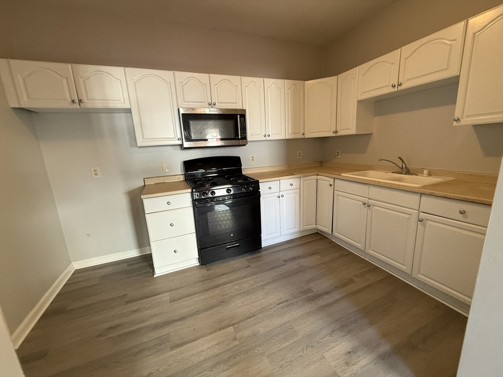 a kitchen with granite countertop a sink cabinets and stainless steel appliances