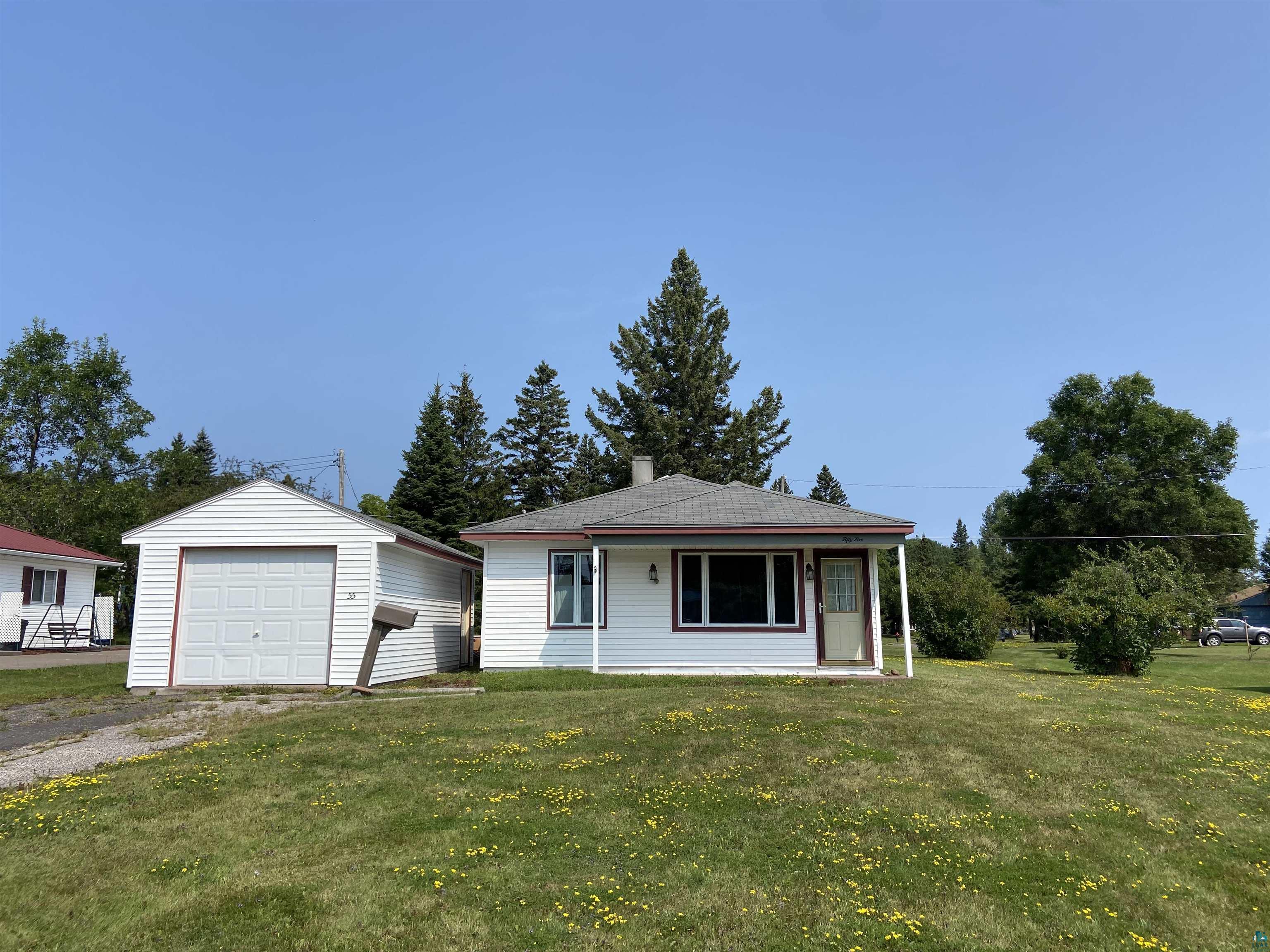 View of front facade featuring a garage, a front yard, and an outdoor structure