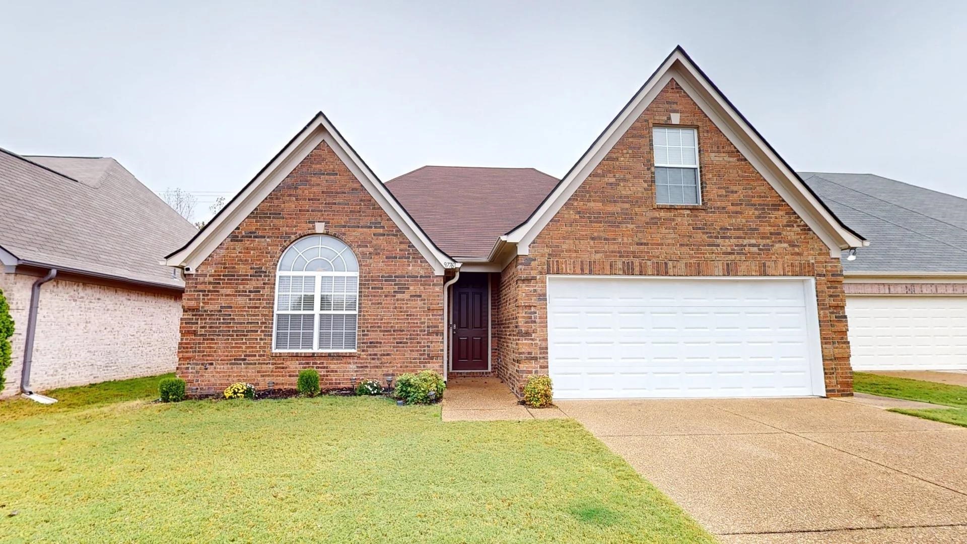 View of front of property featuring a garage and a front lawn