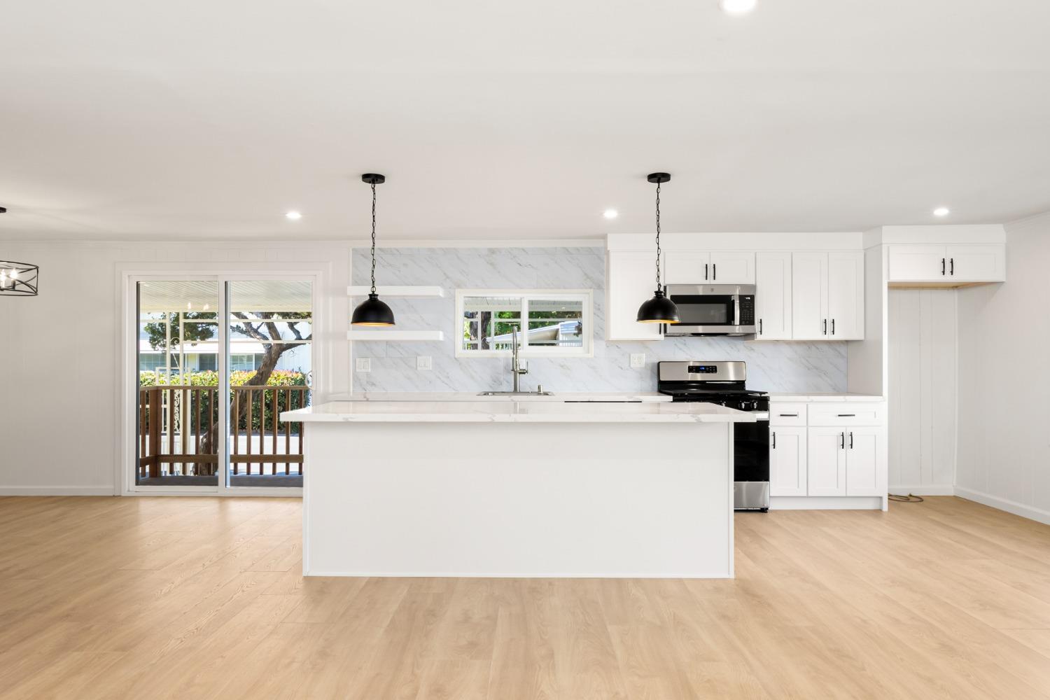 a living room with stainless steel appliances kitchen island hardwood floor and a view of living room